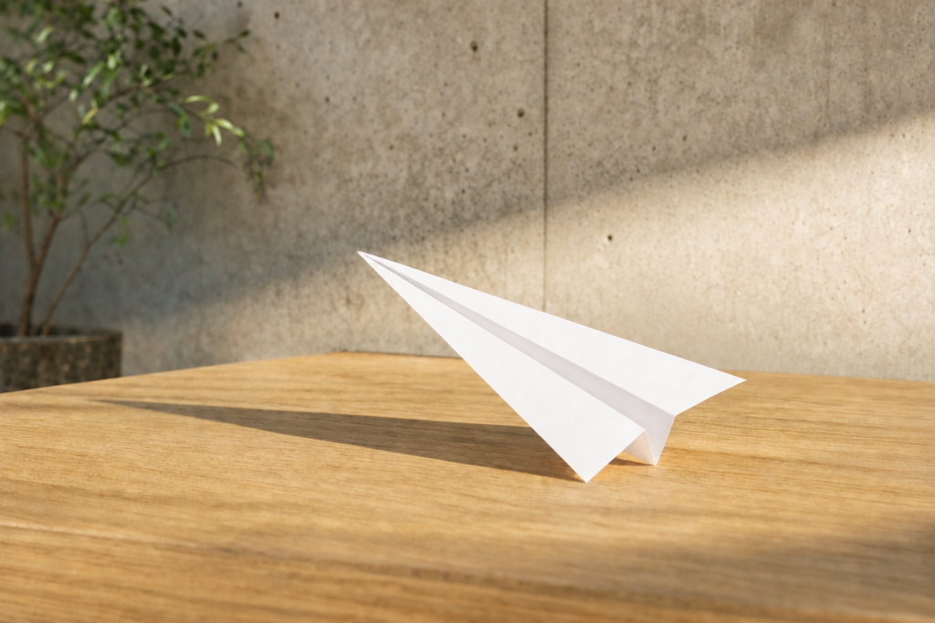 Ein Papierflieger liegt auf einem Tisch.